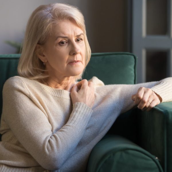 Elderly grey-haired pensive depressed woman sit on sofa alone at home lost on sad thoughts, grandmother thinking about problems difficulties, having senile diseases, mental emotional disorders concept